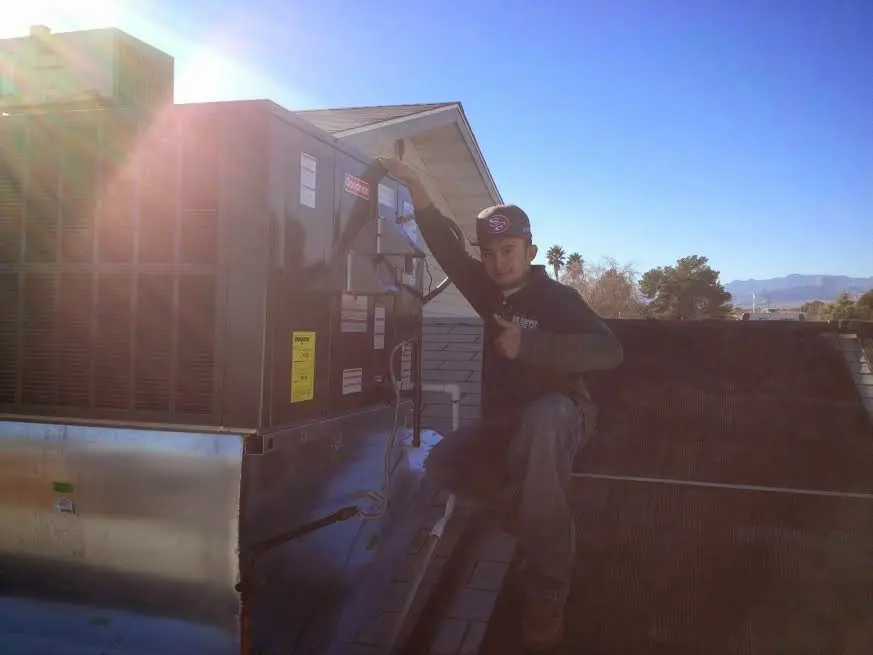 HVAC technician performing Air Duct Cleaning on a rooftop unit in Bulverde